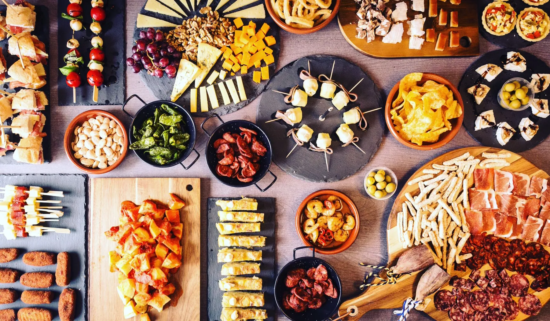 Mesa con una amplia selección de tapas, quesos, embutidos y aperitivos españoles